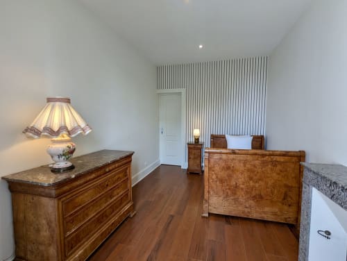 Suite chambre élégante avec mobilier en bois, commode marbrée et lampe d'époque au Domaine du Faure en Chadurie, France