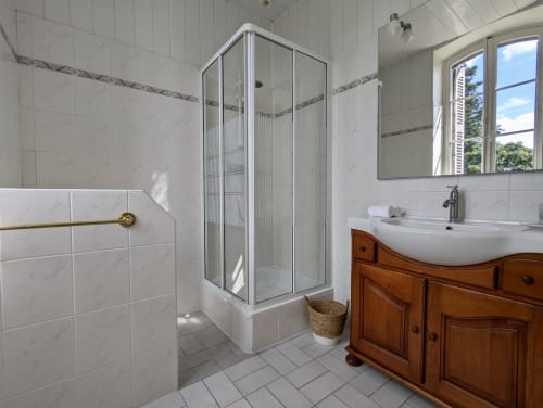 Salle de bains moderne au Domaine du Faure avec douche vitrée, vasque en bois et vue sur le jardin