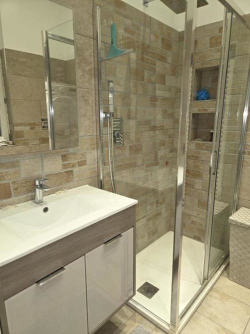 Bagno moderno nell'appartamento Mia Experience di Monza con doccia in vetro, lavabo bianco e finiture in piastrelle neutre