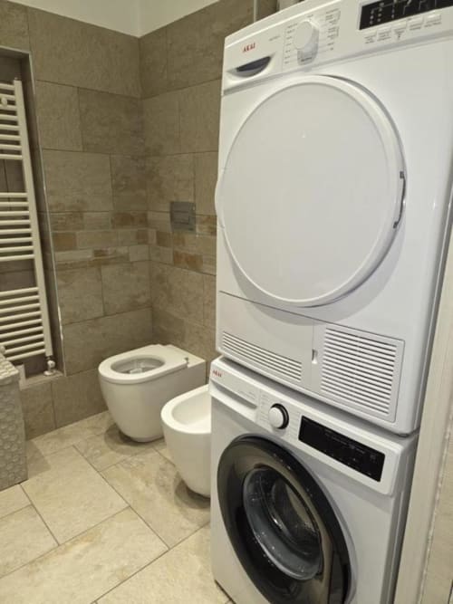 Bagno moderno di Mia Experience Monza con lavatrice e asciugatrice sovrapposte, WC e scaldasalviette