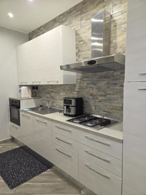 Cucina moderna bianca nell'appartamento Living Monza Arengario di Mia Experience BnB con piano cottura a gas e elettrodomestici in acciaio inox
