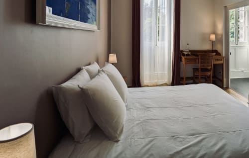 Elegant bedroom at Domaine du Faure with double bed, white pillows, garden views through French doors, and wooden desk in