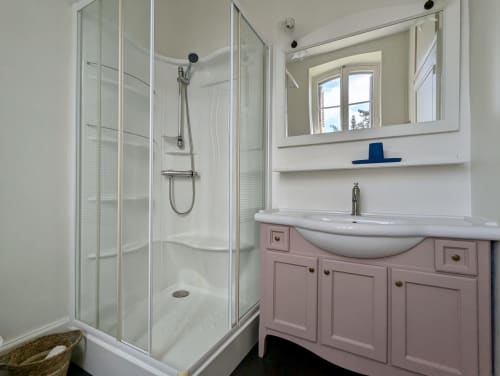 Modern bathroom in Suite Les Clos at Domaine du Faure with pink vanity, white shower enclosure and large mirror