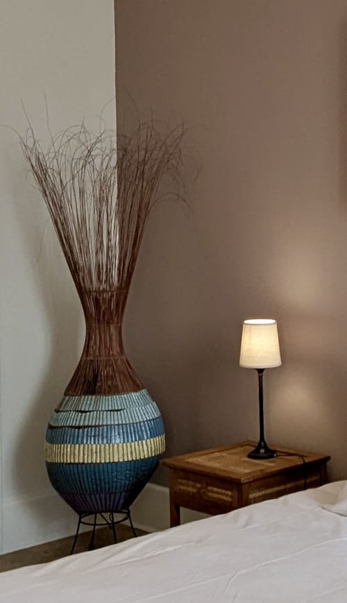 Bedroom corner at Domaine du Faure with decorative woven vase, table lamp, and wooden desk in Suite Les Clos