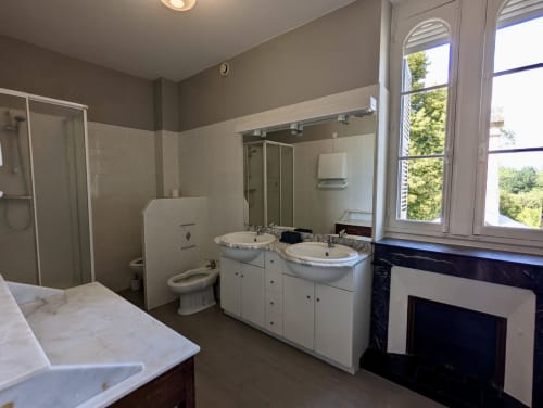 Salle de bains spacieuse de la Suite Le Faure au Domaine du Faure, avec double vasque, WC, douche et vue sur le jardin