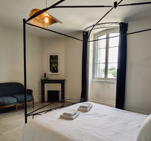 Chambre élégante Suite Le Faure au Domaine du Faure avec lit à baldaquin, cheminée et vue sur le jardin par les portes-fenêtres