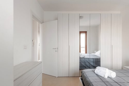 Camera moderna bianca presso Epico Locazioni Turistiche a Brindisi con armadio a specchio e design minimalista
