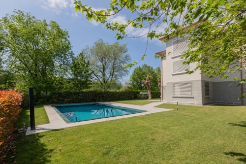 Piscina e giardino Prince Garda a Serniga, Italia con edificio moderno bianco e prato verde rigoglioso