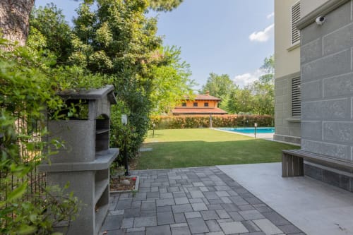 Cortile dell'hotel Prince Garda a Serniga con patio, prato, piscina e edificio con tetto in cotto
