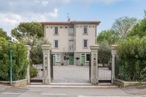 Ingresso dell'hotel Prince Garda a Serniga con elegante facciata color crema, cancellate verdi e giardini curati