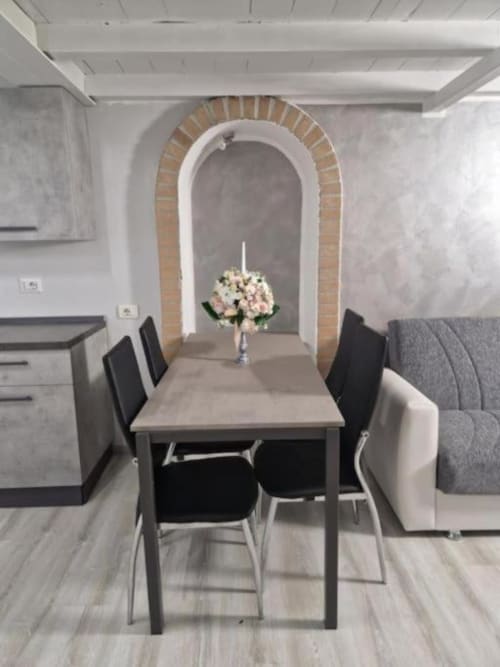 Elegante zona pranzo nella Living Milano Suite di Casa Mia Vacanza con volta in laterizio, tavolo, sedie nere e centrotavola floreale