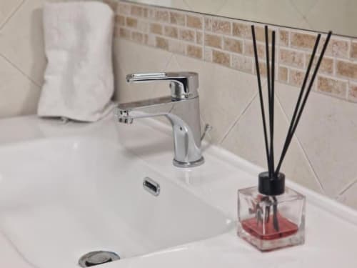Lavabo moderno con rubinetto cromato, porta asciugamani e diffusore di profumo rosso a Casa Mia Vacanza