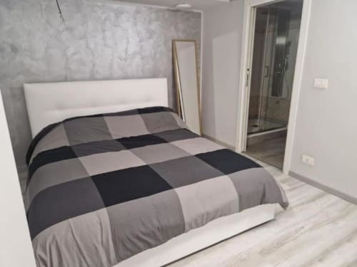 Camera moderna in Casa Mia Vacanza Milano Suite con coperta a quadri, testata bianca e bagno privato