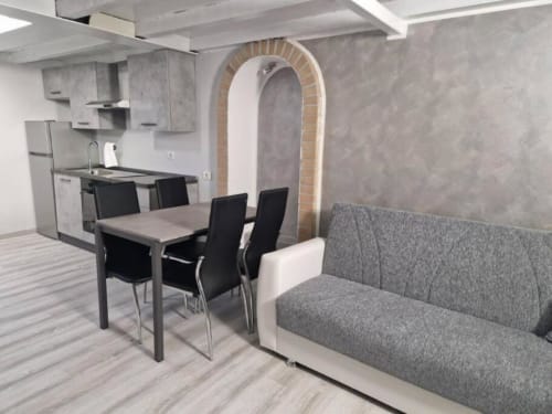 Zona living moderna con tavolo da pranzo, divano grigio, cucina e porta ad arco - Appartamento Casa Mia Vacanza Milano Suite