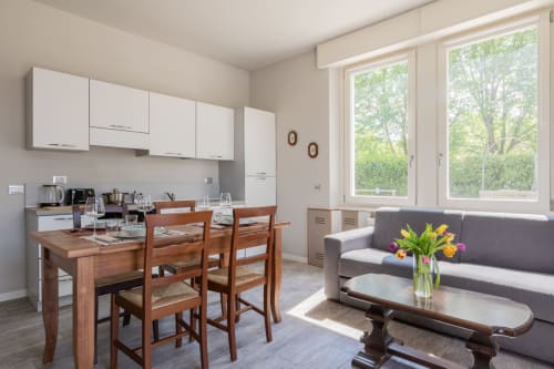 Moderna cucina open-plan e zona living all'hotel Prince Garda di Serniga, Italia, con tavolo da pranzo e divano grigio