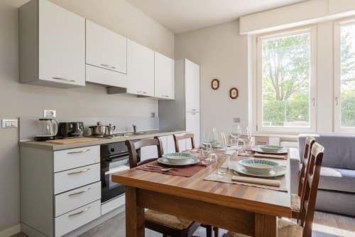 Moderna zona cucina-pranzo dell'hotel Prince Garda con mobili bianchi, tavolo in legno preparato per la cena e ampie finestre
