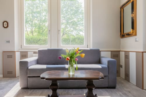 Moderna zona living dell'hotel Prince Garda a Serniga con divano grigio, tavolino in legno e tulipani freschi