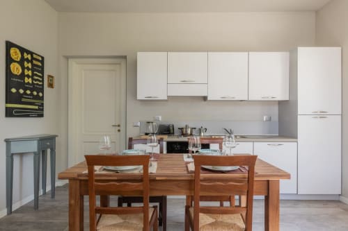 Cucina moderna e zona pranzo a Prince Garda con arredamenti bianchi, tavolo in legno e sedie a Serniga