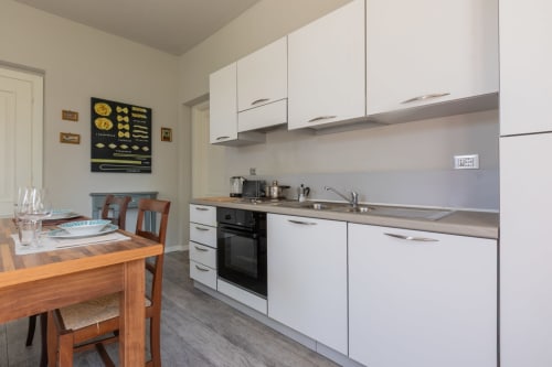 Cucina moderna con mobili bianchi, zona pranzo presso Prince Garda, Serniga