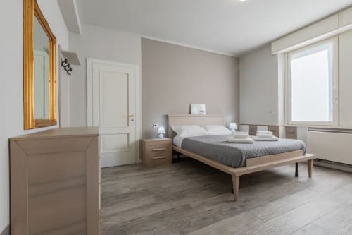 Camera moderna dell'hotel Prince Garda a Serniga con letto in legno, arredi beige e finestre luminose