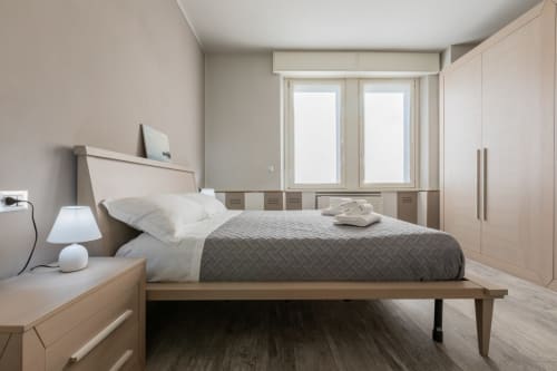 Camera moderna dell'hotel Prince Garda a Serniga con letto queen size, biancheria bianca, plaid grigio, mobili in legno e ampie finestre