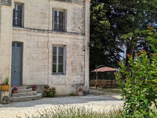 Cour de mas en pierre du Domaine du Faure avec coin détente et parasol à Chadurie
