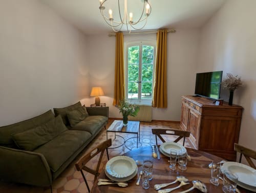 Élégante salle à manger et séjour du Gîte Le Chêne au Domaine du Faure, table dressée, canapé vert et vue sur le jardin