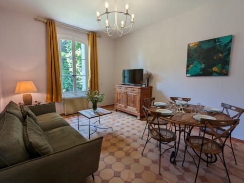 Élégant séjour et salle à manger au Gîte Le Chêne du Domaine du Faure, avec canapé, mobilier en bois, TV et vue sur le jardin