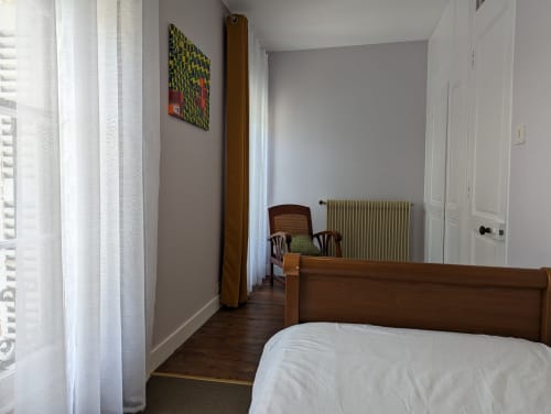 Chambre spacieuse au Gîte Le Chêne du Domaine du Faure avec lit en bois, vue sur le jardin, radiateur et équipements modernes