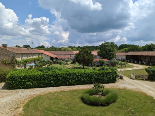 Vue du jardin du Gîte Le Chêne du Domaine du Faure : bâtisses en pierre, pelouses soignées et paysage campagnard