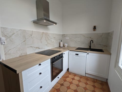 Cuisine moderne du Gîte Le Chêne au Domaine du Faure avec armoires blanches, comptoirs en bois, hotte inox et marbre