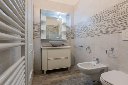 Bagno moderno dell'hotel Prince Garda a Serniga con lavabo a catino, bidet, wc e rivestimenti in piastrelle a righe