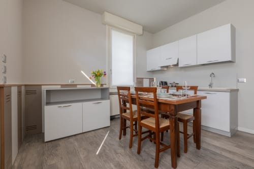 Cucina moderna dell'hotel Prince Garda a Serniga con mobili bianchi, tavolo in legno e ampia luminosità naturale dalla finestra