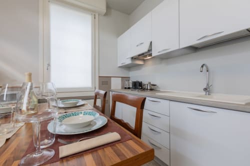Cucina moderna con zona pranzo all'hotel Prince Garda di Serniga, con mobili bianchi e tavolo in legno.