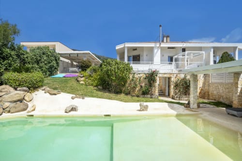 Luxury villa in Quartu Sant'Elena with pool, sandy beach area, and modern white architecture under clear skies