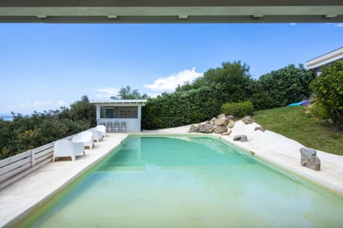 Luxurious swimming pool at Top Villas Sardinia in Quartu Sant'Elena with turquoise water, white loungers, and Mediterranean