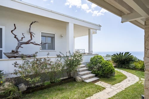Modern villa patio with ocean view, landscaped garden, and steps leading to sea-facing terrace in Quartu Sant'Elena, Sardinia