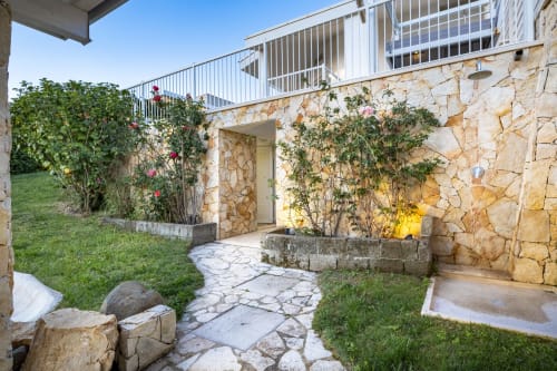 Stone patio with blooming flowers at Top Villas Sardinia, Quartu Sant'Elena, featuring modern terrace and manicured grounds