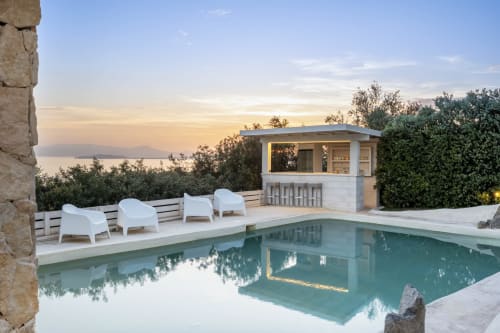 Luxury villa pool at sunset overlooking the Mediterranean Sea in Quartu Sant'Elena, Sardinia, with modern lounge area and bar