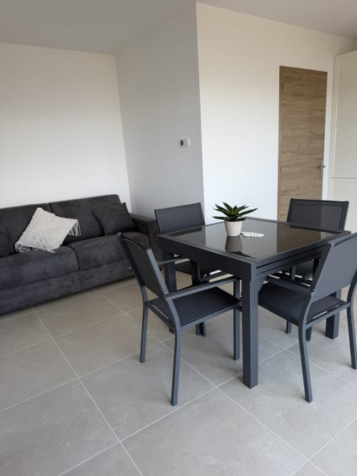 Salle à manger moderne de l'appartement L'écrin de Paradis au Petit Coin de Paradis, Alata avec table noire, chaises et canapé foncé
