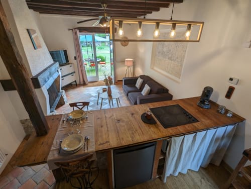 Cuisine ouverte et salon à la chaumière Domaine du Faure avec poutres en bois, comptoir de salle à manger et vue sur le jardin