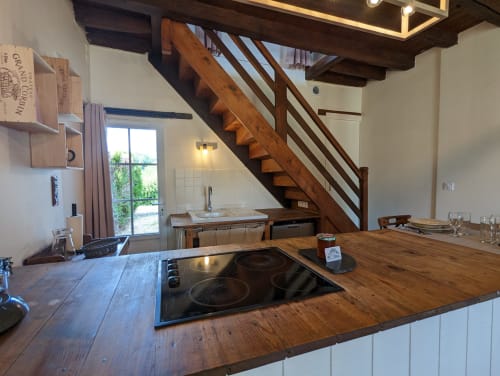 Cuisine contemporaine du gîte Le Rose au Domaine du Faure avec comptoir bois, plaque induction et escalier en bois