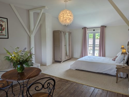 Chambre spacieuse du Gîte Le Rose au Domaine du Faure avec vue sur le jardin, luminaire suspendu moderne et mobilier élégant