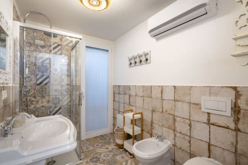 Spacious bathroom at Top Villas Sardinia featuring corner tub, shower, bidet, and decorative tile work in Quartu Sant'Elena