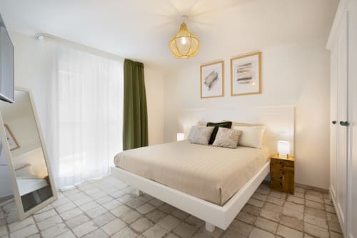 Modern bedroom at Top Villas Sardinia with white bed, golden pendant light, and olive curtains in Quartu Sant'Elena
