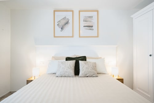 Modern bedroom at Top Villas Sardinia with white bedding, patterned pillows, and framed artwork above the bed