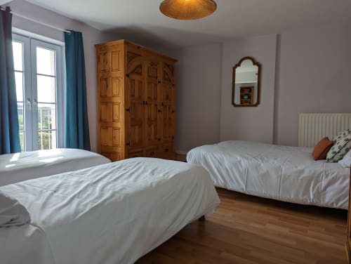 Chambre twin avec armoire en bois et vue sur le jardin au Gîte Le Châtaigne, Domaine du Faure à Chadurie