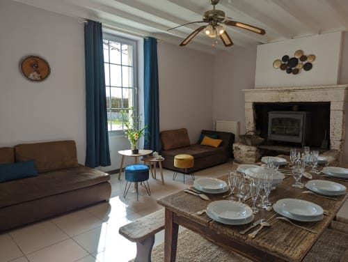 Séjour et salle à manger ouverts du Gîte Le Châtaigne au Domaine du Faure avec canapé marron, cheminée et table dressée