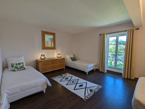 Chambre lumineuse au gîte Domaine du Faure avec deux lits simples, commode en bois et portes vue jardin à Chadurie, France