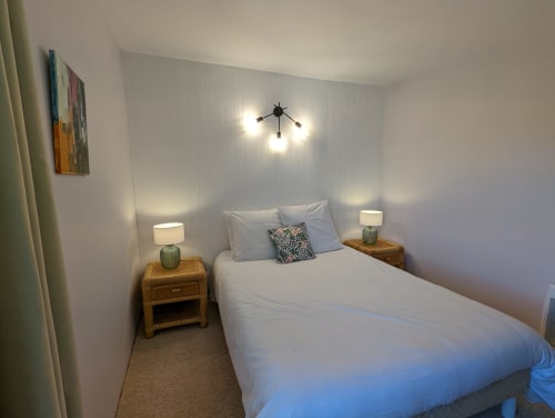 Chambre moderne au Domaine du Faure à Chadurie avec lit queen-size, tables de nuit en bois, luminaire suspendu et vue sur le jardin
